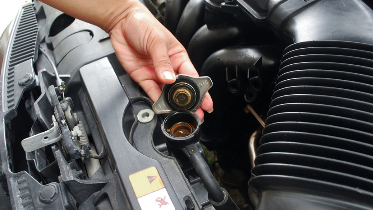 Image of person opening radiator cap on Subaru car. Cooling System Repair