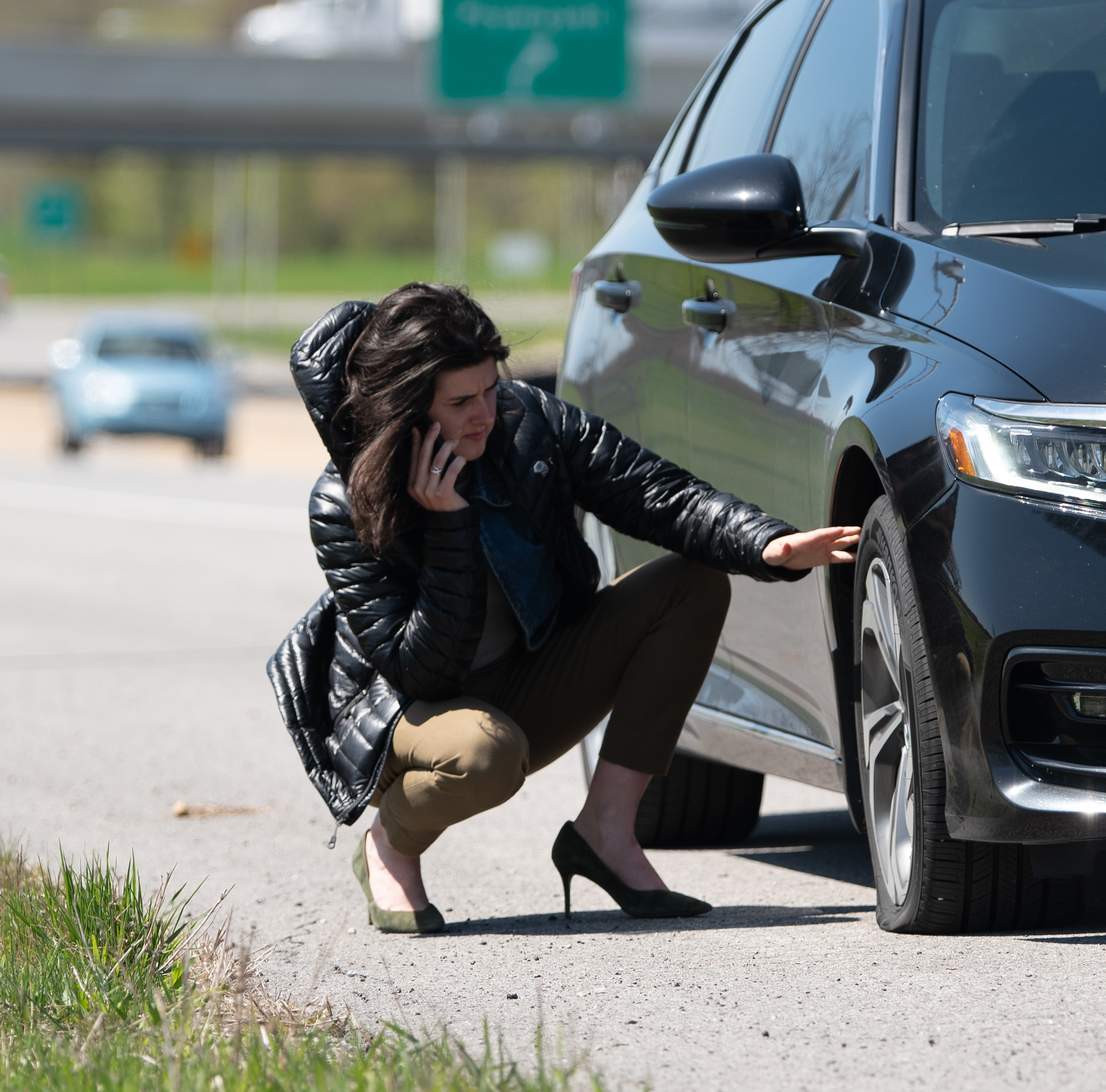 Image of woman experiencing flat tire on expressway